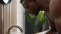 Bath morning routine African American man washing face with pouring cold water in bathroom sink ethnic male guy wash Royalty Free Stock Photo