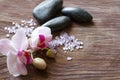 Bath salt, orchid and massage stones on wooden background, spa concept
