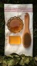 Bath soap lies on a light towel. A birch broom, a body brush and natural honey lie nearby. Set of accessories for sauna and steam
