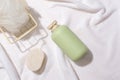 A bath sponge in an iron basket, a bar of soap and an unlabeled bottle of shower gel are displayed on a white fabric background. Royalty Free Stock Photo