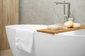 Soft bath towel and personal care products on tub tray in bathroom Royalty Free Stock Photo