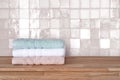 Bath towel pile on wooden surface before ceramic tile wall