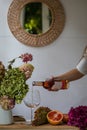 Bath tub with flower petals, grapefruit slices, bunch of grapes and woman`s hand holding a bottle of wine Royalty Free Stock Photo