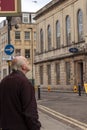 An elderly caucasian man wearing winter coat is standing on the sidewalk,