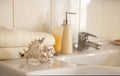 Bath white cotton towels, ceramic bottle with shampoo, tube with cream and cockleshell on Blurred bathroom interior background Royalty Free Stock Photo