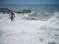 Bather on the beach during a heavy storm. Waves crashing powerfully to shore