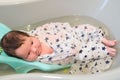 Bathing a baby. bathes her son in a small plastic bath Royalty Free Stock Photo