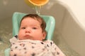 Bathing a baby. bathes her son in a small plastic bath Royalty Free Stock Photo