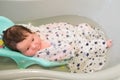 Bathing a baby. bathes her son in a small plastic bath Royalty Free Stock Photo