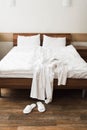 Bathrobe over bed in hotel room with slippers Royalty Free Stock Photo