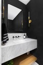 A bathroom with black wallpaper and a marble vanity.