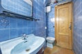 Bathroom with blue porcelain sink, mirror, shower cubicle with glass partition and blue tiles and pinewood door with radiator on Royalty Free Stock Photo