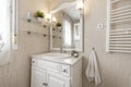 Bathroom with cream tiled walls and floors and white wooden bathroom cabinet with white porcelain sink with mirror and matching