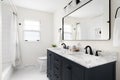 A bathroom with a dark blue cabinet, marble countertop, and subway tile shower. Royalty Free Stock Photo