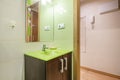 Bathroom with dark wood cabinet, pistachio green glass sink, mirror with sconces and jarred tiles on the wall