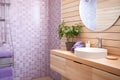 Bathroom design. The bathroom is lined with purple tiles. The room has a wooden cabinet, a mirror and a hanger with