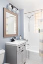 A bathroom detail with a grey cabinet and white hexagon tile floor.