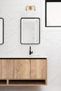 A bathroom detail with a wood cabinet and black faucet and mirror. Royalty Free Stock Photo