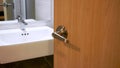 Bathroom door handles,door with stainless knob door half open in front of interior bathroom white sink of washing hands and mirror Royalty Free Stock Photo