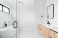 A bathroom with a floating wood cabinet, freestanding tub, and marble hexagon tile floor.