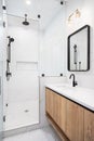 A bathroom with a floating wood cabinet and white marble tiled shower. Royalty Free Stock Photo