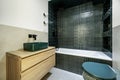 A bathroom with green stoneware in the bathtub and cream-colored