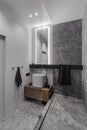 Bathroom in grey tones, stylish in modern design, dark wooden tumble, glass and mirror. Chrome crane. Black towel