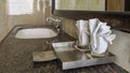 The bathroom has a stainless steel tray with two glasses and folded napkins on a marble countertop.