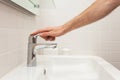 Bathroom interior. Bright bathroom with new tiles. New washbasin, white sink and large mirror. Hand open water tap. Royalty Free Stock Photo