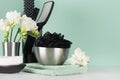 Bathroom interior in green with black accessories mirror, bath sponge, soap, towel, flowers, gel dispenser, toothbrush, brush. Royalty Free Stock Photo