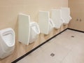 Bathroom interior in light beige and white colors. Oval ceramic urinal. Place of need for men. Restroom in public areas of urban Royalty Free Stock Photo