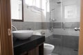 Bathroom interior with white round sink and chrome faucet in a modern bathroom with a toilet and shower. Water flowing Royalty Free Stock Photo