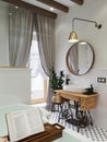 Bathroom interior. Wooden tray with a book and a glass. Washbasin on a sewing machine cabinet.