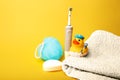 Bathroom items. Electric toothbrush, white towel, blue washcloth, white soap, rubber duck for bathing on a yellow Royalty Free Stock Photo