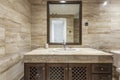 Bathroom with marble tiled walls, wood framed mirror and marble