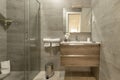 Bathroom with oak chest of drawers with imitation marble tiles, frameless mirror on the wall, stainless steel accessories, clean Royalty Free Stock Photo