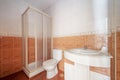 Bathroom with one-piece white resin curvature washbasin cabinet, square shower cabin and brown tiles on the floor and half of the