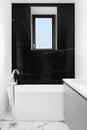 A bathroom\'s freestanding tub and black marble wall.