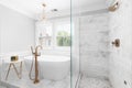 A marble lined shower and standalone tub with gold faucets and chandelier.