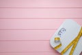 Bathroom scale, measuring tape and space for text on pink wooden floor, top view. Weight loss concept Royalty Free Stock Photo