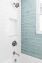 A shower with white and blue subway tiles.