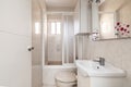 Bathroom with shower with sliding door screen, cream-colored tiles on walls and floors and bathroom cabinet with white porcelain Royalty Free Stock Photo