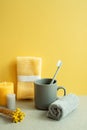 Bathroom shower towel and toothbrush, cup, candle, dry flower on gray table. yellow background Royalty Free Stock Photo