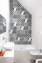 Bathroom with shower unit, toilet, bidet and basin unit, with black and white monochrome patchwork tiles and high ceiling Royalty Free Stock Photo