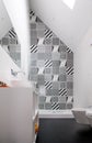 Bathroom with shower unit, toilet, bidet and basin unit, with black and white monochrome patchwork tiles and high ceiling Royalty Free Stock Photo