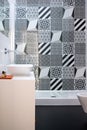 Bathroom with shower unit, toilet, bidet and basin unit, with black and white monochrome patchwork tiles and high ceiling Royalty Free Stock Photo