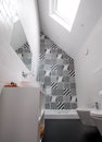 Bathroom with shower unit, toilet, bidet and basin unit, with black and white monochrome patchwork tiles and high ceiling Royalty Free Stock Photo