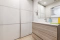 Bathroom with sink cabinet with wooden drawers, frameless square mirror and large sliding-door closet covering one wall Royalty Free Stock Photo