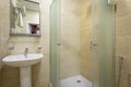 Bathroom,tiles and bright colors of broom, shower with frosted doors,mirror above the sink. Hanging a towel over the toilet on a h