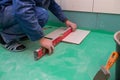 Bathroom tiles replacing. Caucasian worker is installing brand new ceramic tiles in bath is inder construction Royalty Free Stock Photo